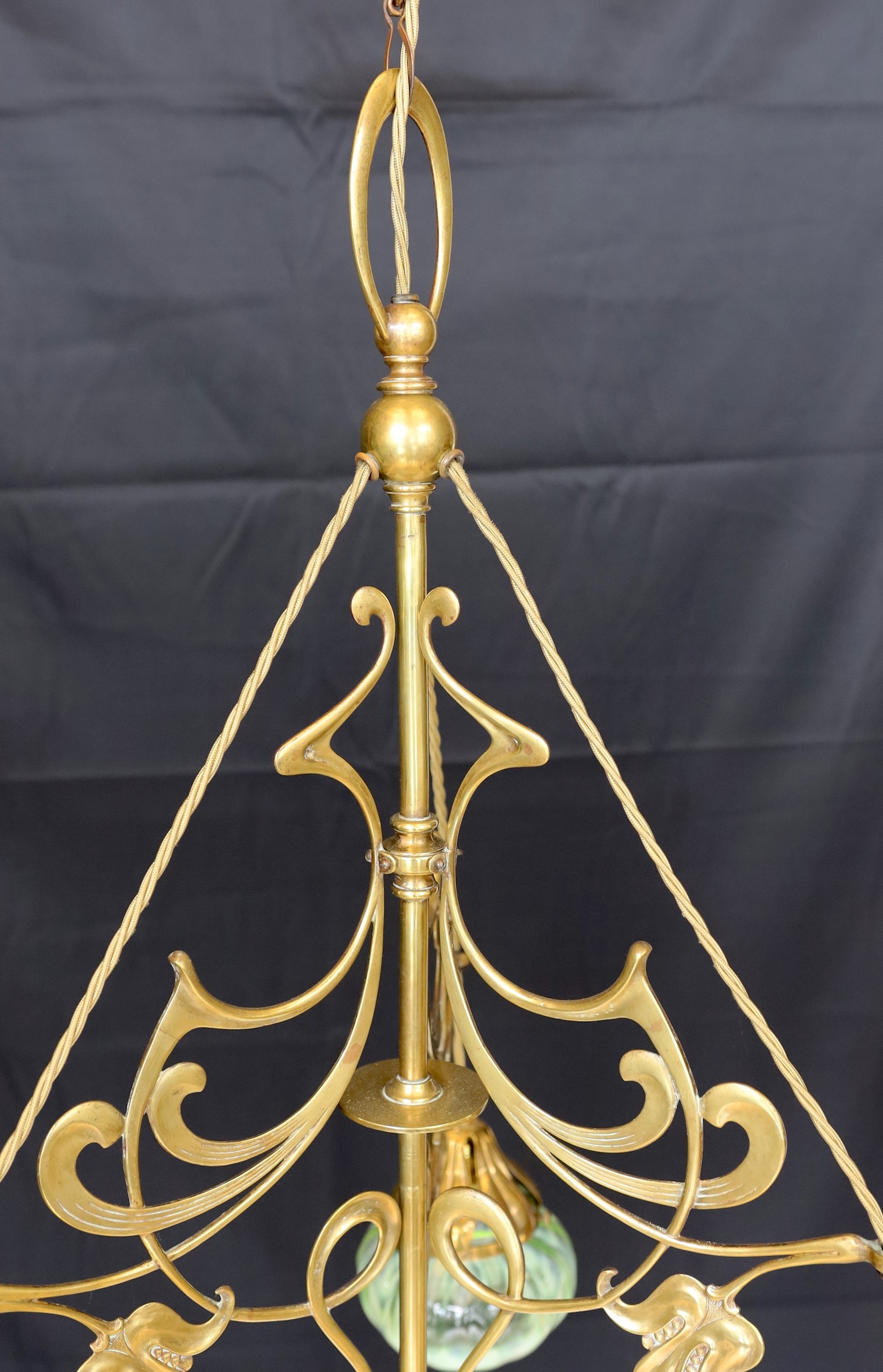 An English Arts & Crafts brass light fitting with scrolling foliate branches and tinted iridescent glass shades, height 68cm. width 46cm
